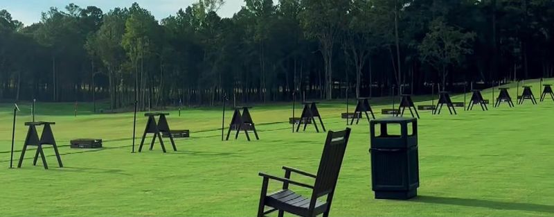 Grass driving range at the Golf Performance Center at Eagle’s Bluff in Bullard, TX, with hitting stations and tall pine trees