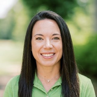 Jessica Simpson, PGA Associate and Teaching Professional, smiling outdoors in a green golf shirt